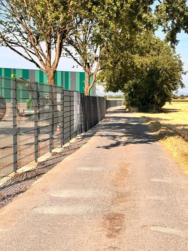 Zaun mit Sichtschutz entlang eines Wegs an einem Gewerbegrundstück